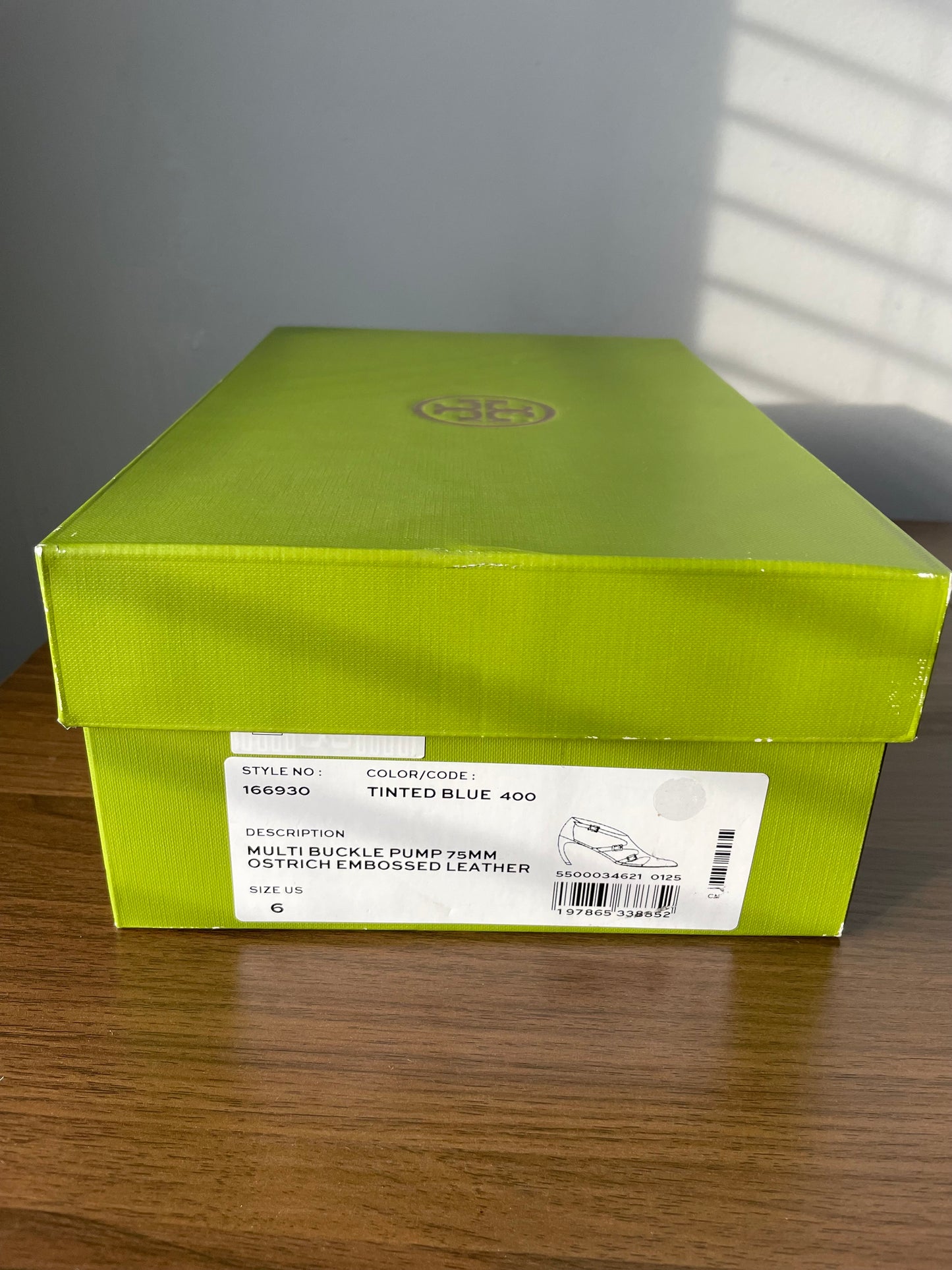 Tory Burch green shoe box with a label on a wooden surface