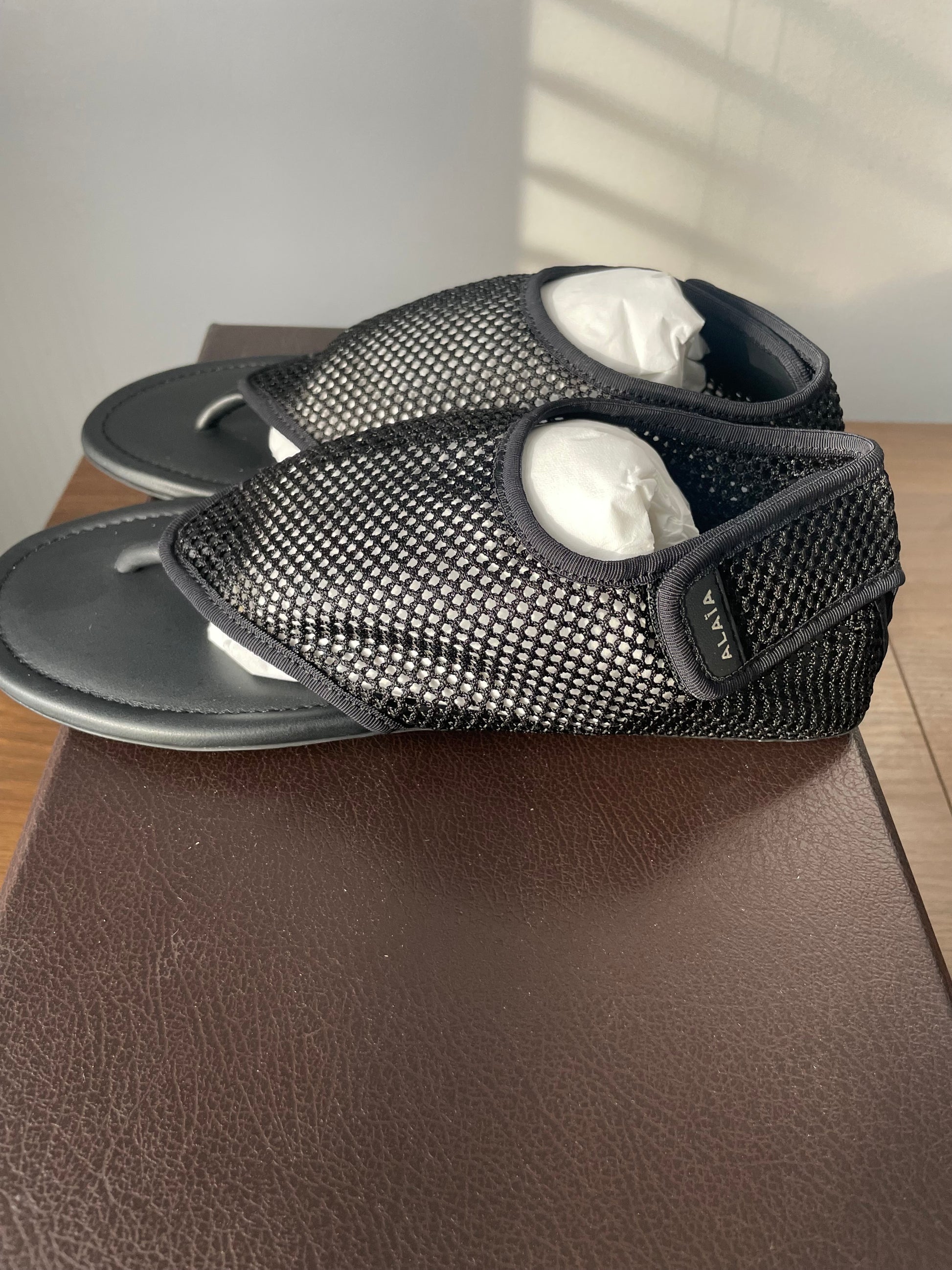 Alaia black mesh thong flat sandals side view on box