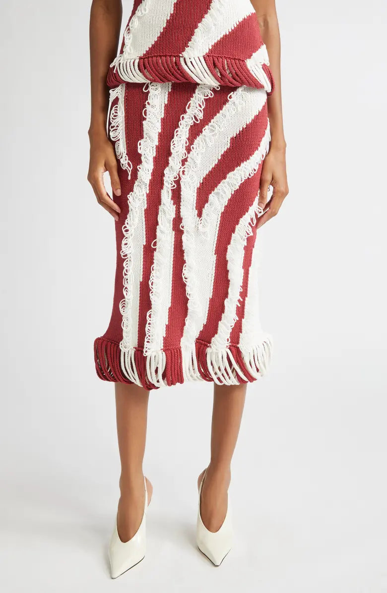 Model wearing Diotima Roaring Knit skirt in red + white with white pumps