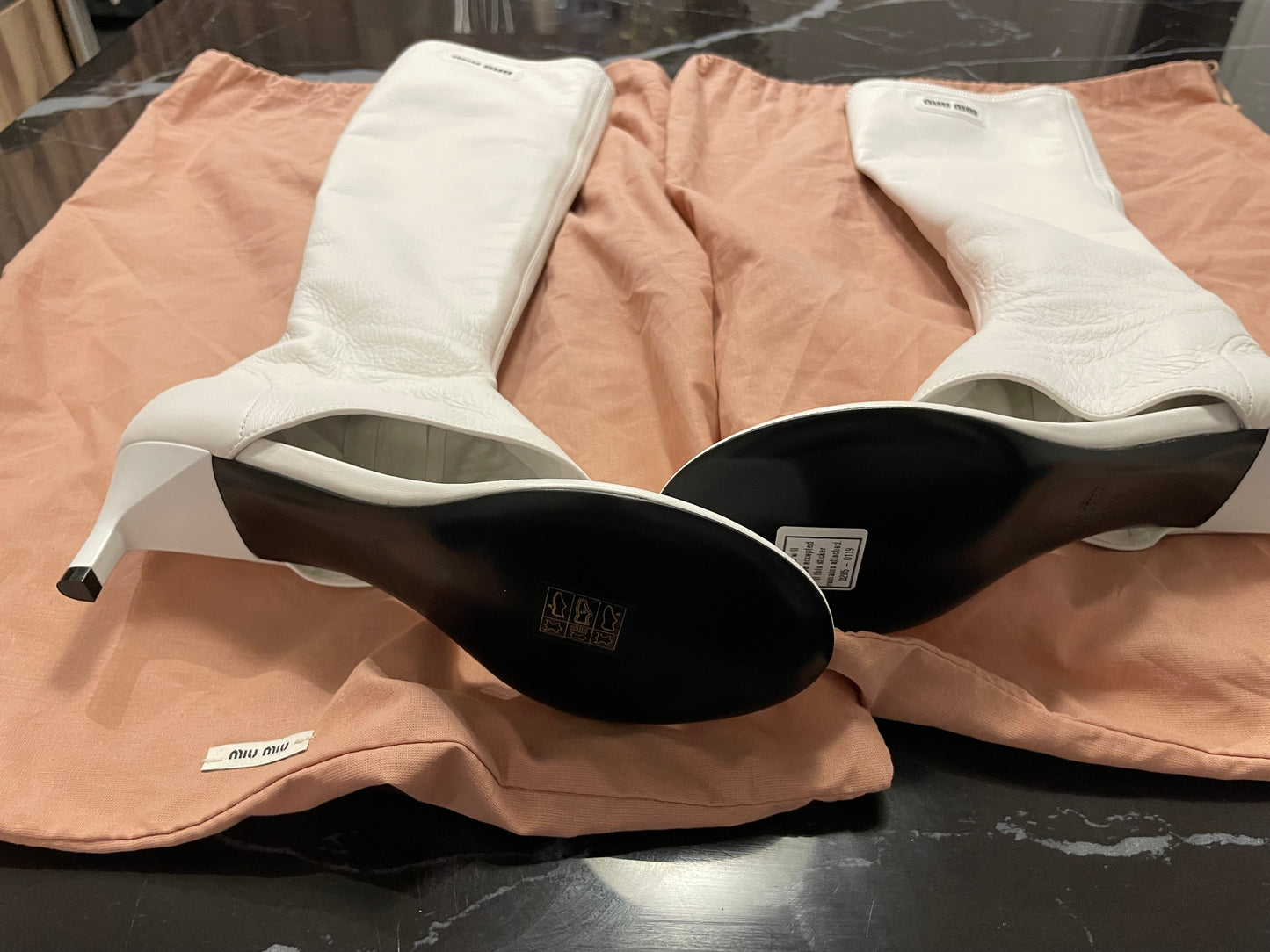 White Miu Miu Leather Thong Sandal Boots Bottom view on Pink Dustbags against black marble