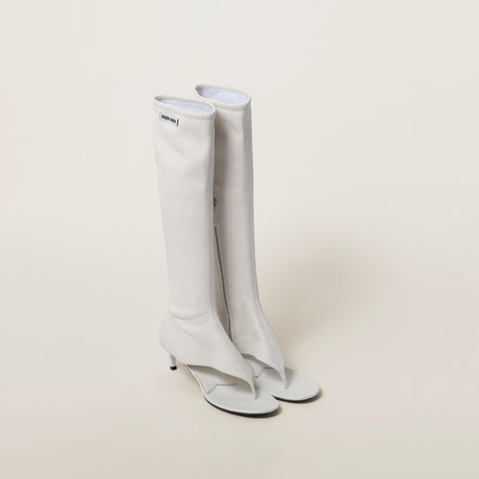 White leather knee-high Miu Miu open-toe boots on a light gray background