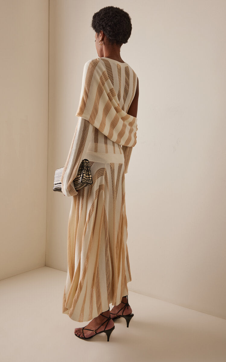 Back view of model wearing a striped dress from Diotima with a neutral background