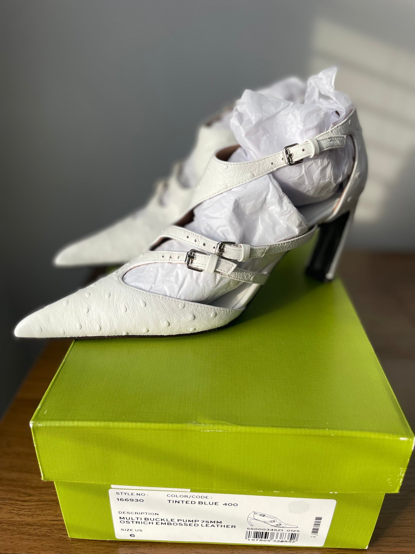 Side view of White Tory Burch Multi-Buckle Pumps on Green Shoe box