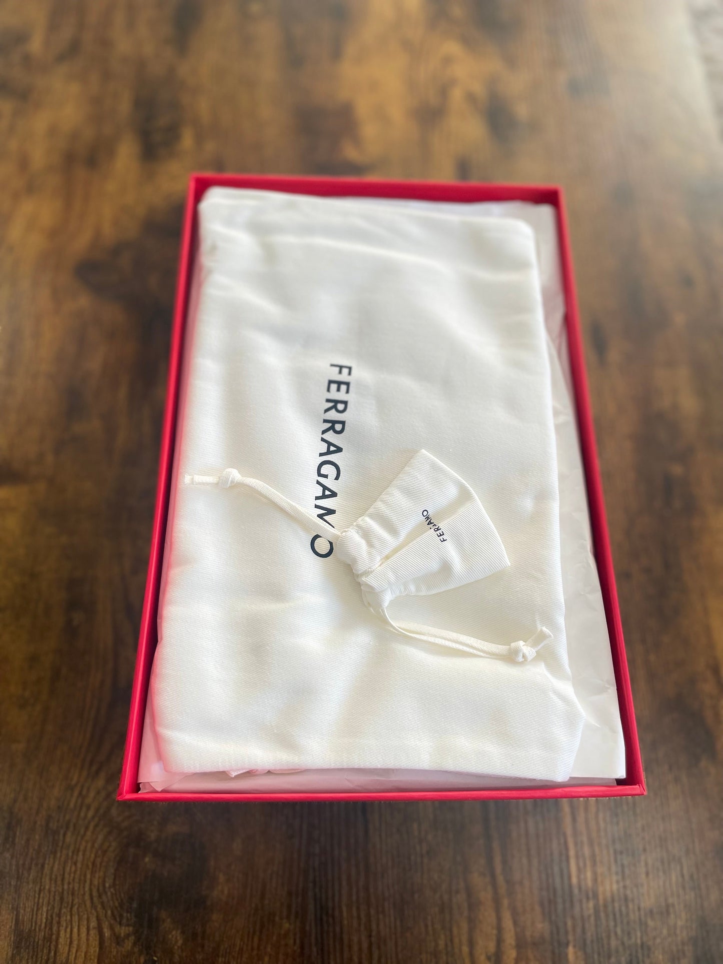 Ferragamo dustbag inside a red box on a wooden surface