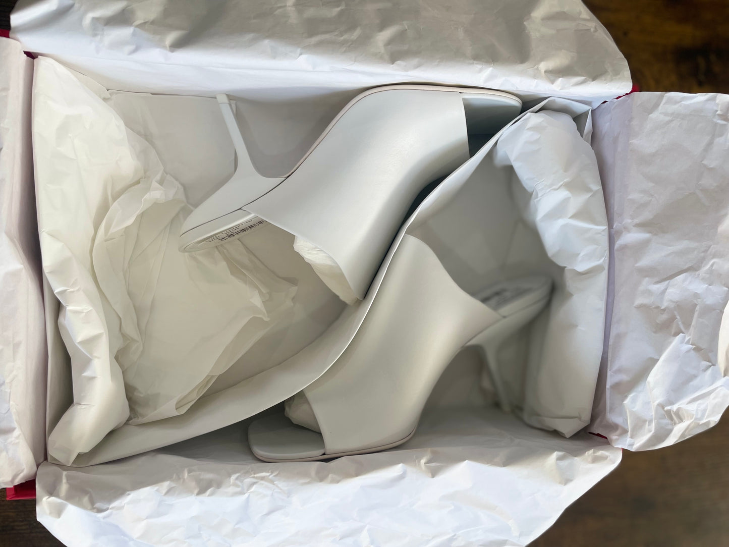 Side view of Ferragamo white leather sandals in shoebox  