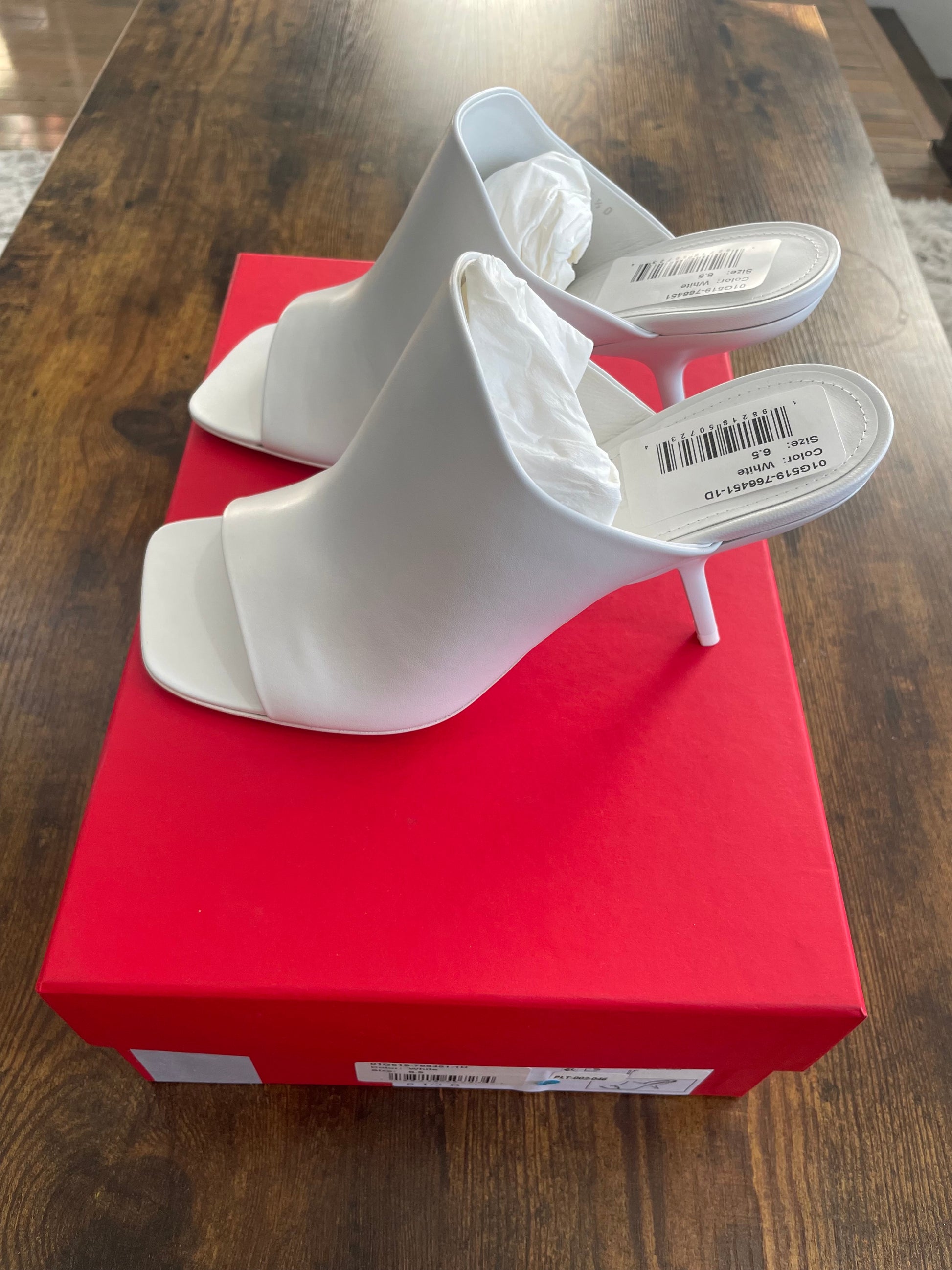 Side view of white square toe Ferragamo shoes on red shoebox