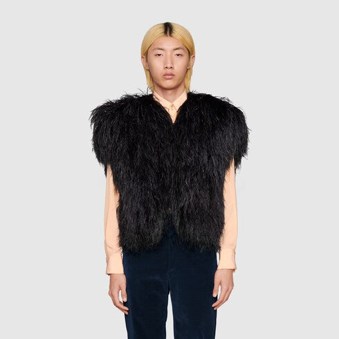 Model wearing black Gucci ostrich feather vest in front of grey background